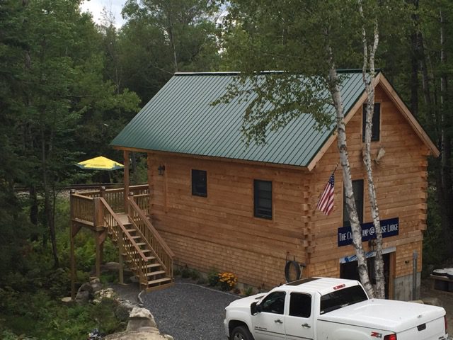 Wooden cabin with truck in forest setting.
