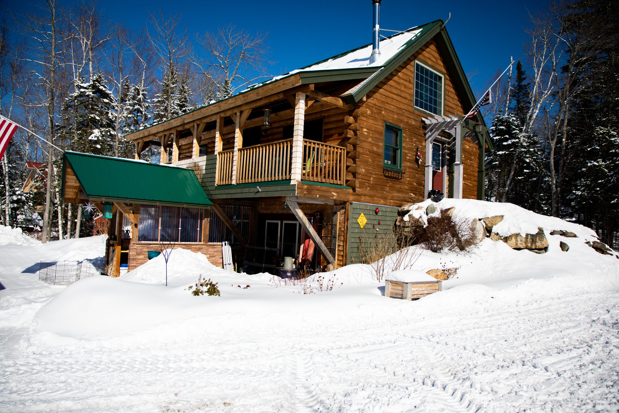 A wooden cabin with a balcony surrounded by snow.