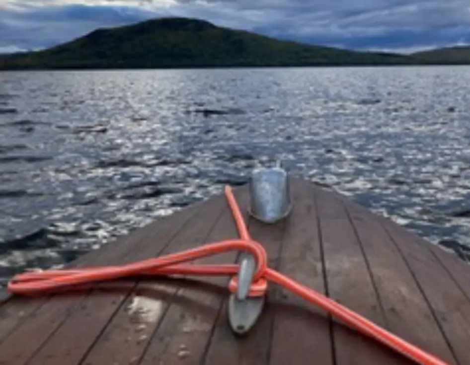 View from a boat bow on a lake with hills in the distance.