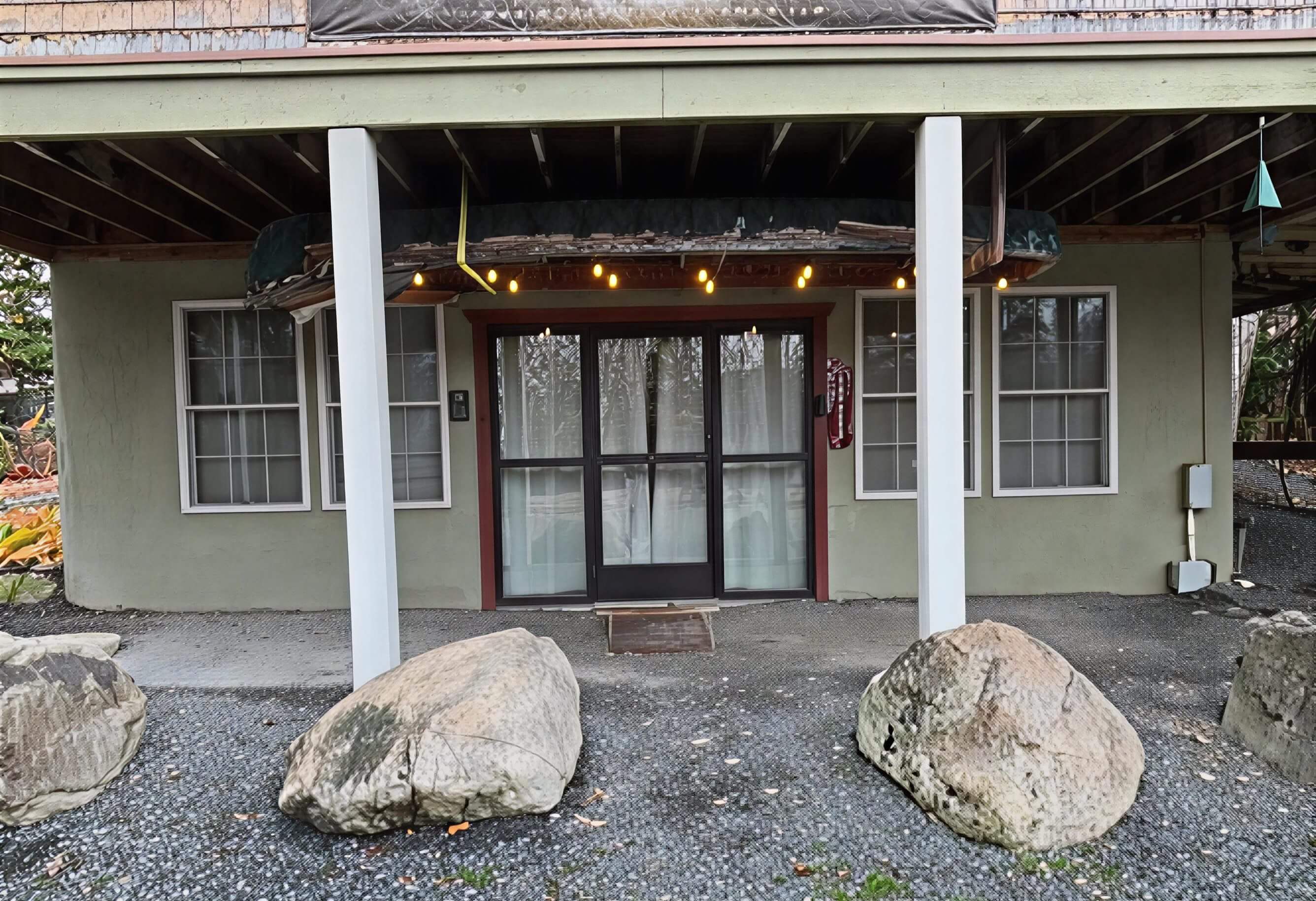 Entrance to a rustic building with large rocks and string lights.