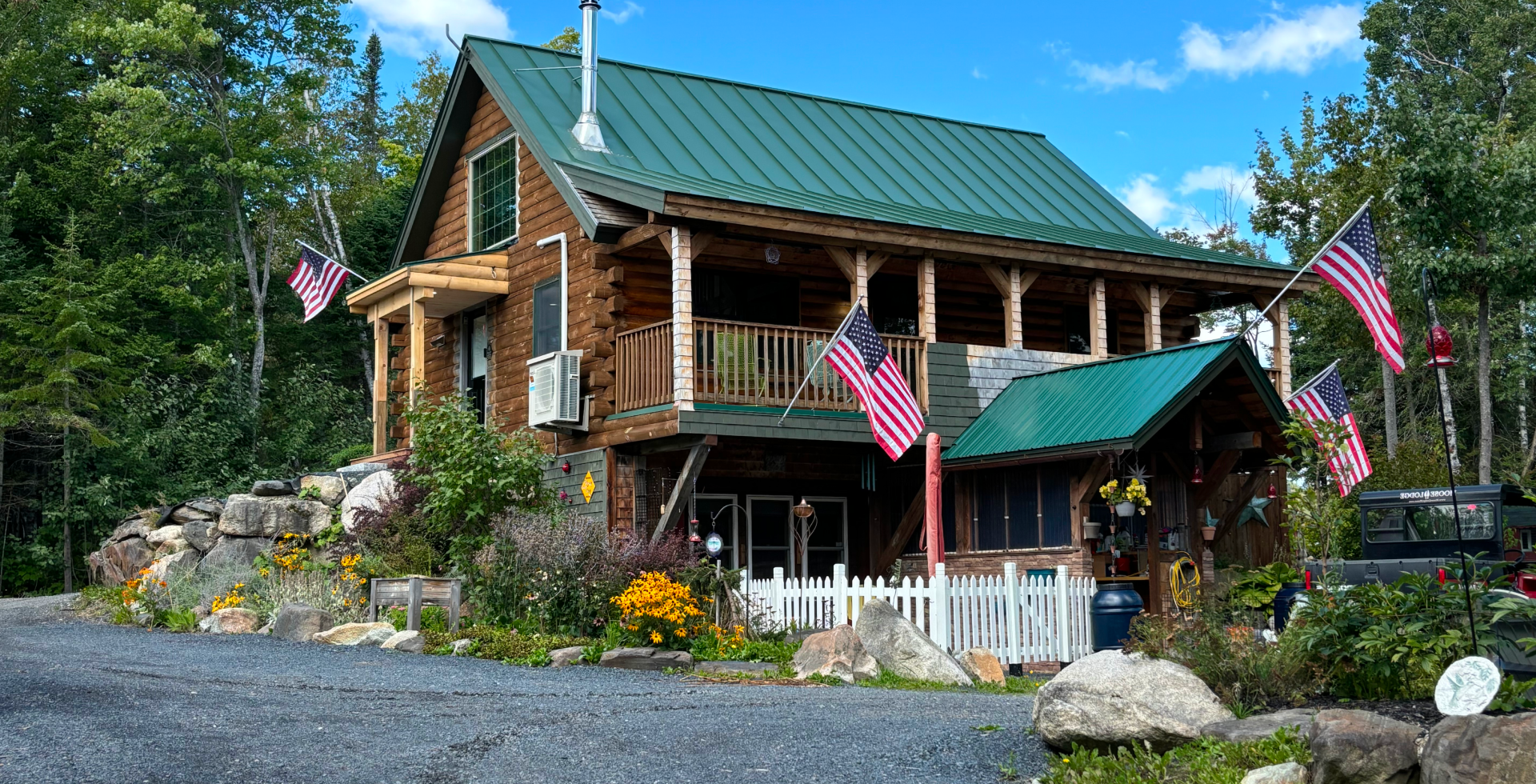 Charming wooden house with green roof and an American flag in the garden.